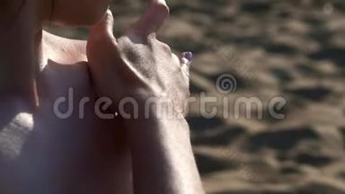 穿着黑色泳衣的海滩上的女孩涂了防晒霜或防晒霜。 在海边的沙滩上